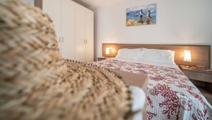 A hotel room with a bed, nightstands, a painting, and a wardrobe. - Spacious apartment with terrace in Lignano (Lignano Sabbiadoro)