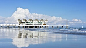 A waterfront building with multiple arched windows and a pier extending into the water. - Stylish flat near beach and center in Lignano (Lignano Sabbiadoro)