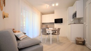 Un appartement moderne et bien éclairé, comprenant un espace de vie, un coin repas et une cuisine.