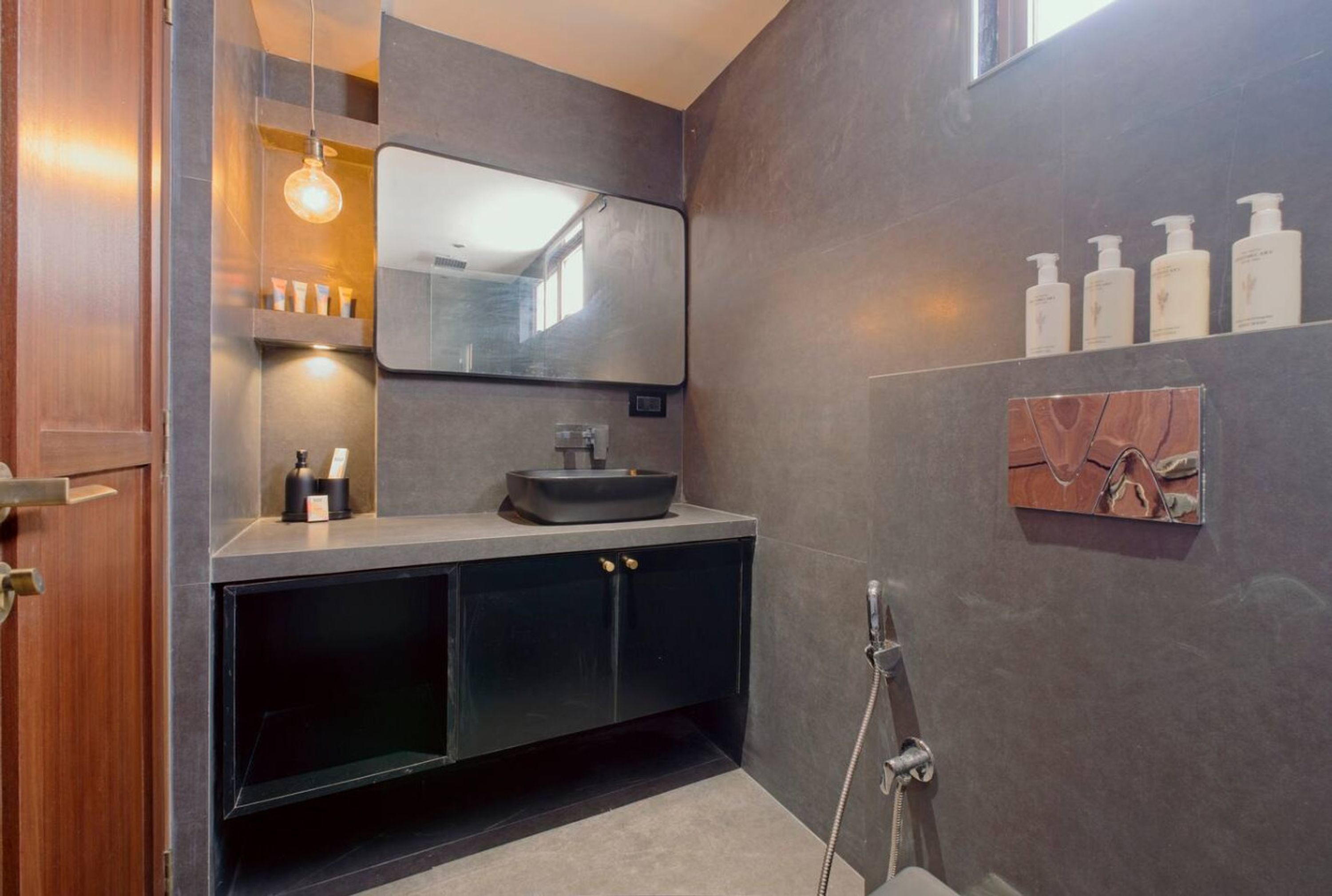 A modern bathroom with a dark-toned vanity, a large mirror, and a shower area.