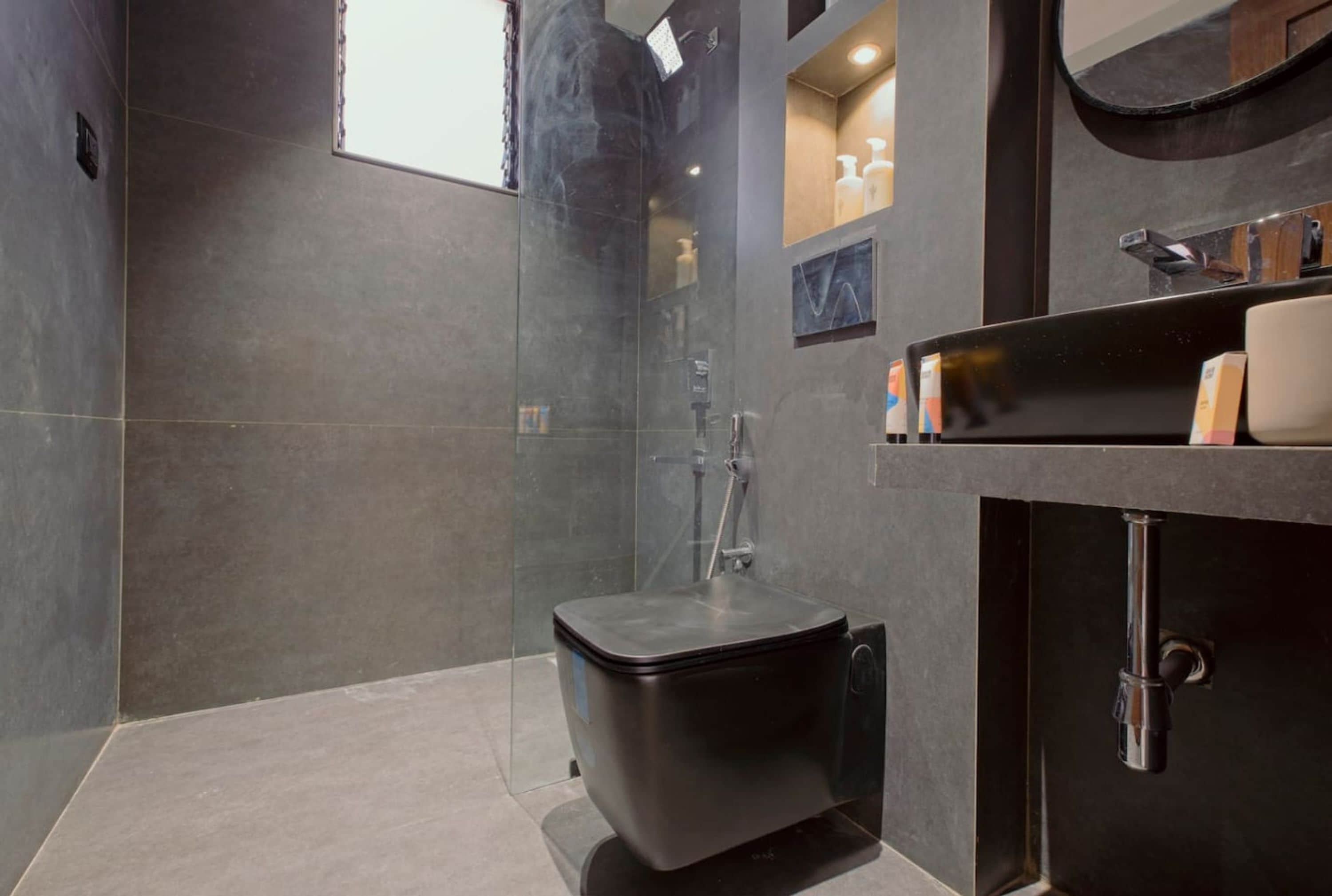 A modern bathroom with a glass-enclosed shower, a black sink, and a mirror above it.