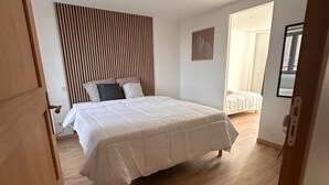 A bedroom with a bed, wooden floor, and a slatted headboard. - Au petit Langres: Downtown accommodation (Langres)