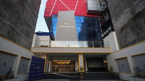 A modern building with a prominent Siddhartha sign, featuring a glass facade and a red and blue color scheme. - Siddhartha Hotel Damauli (Byas)