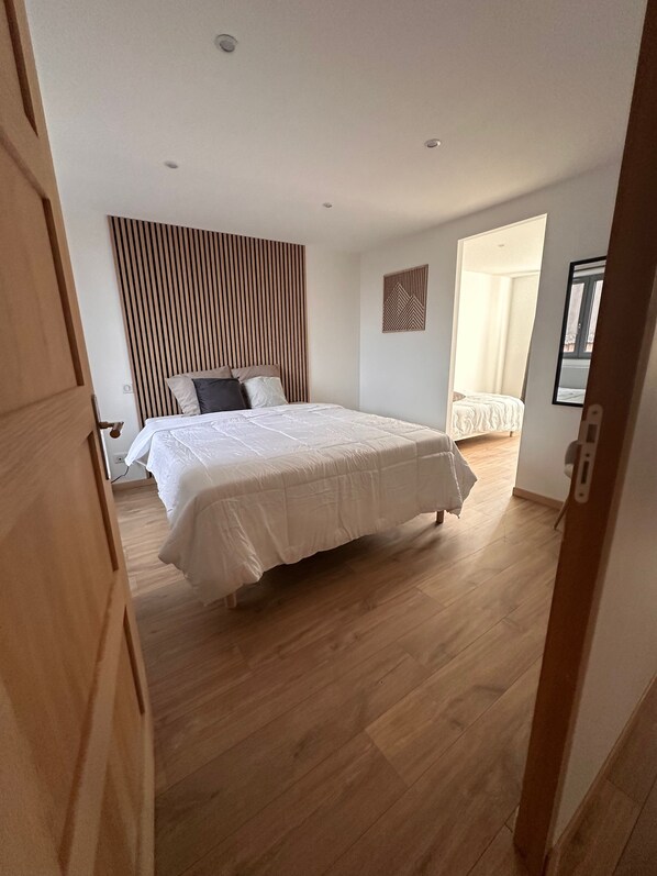 A bedroom with a bed, wooden floor, and a slatted headboard.