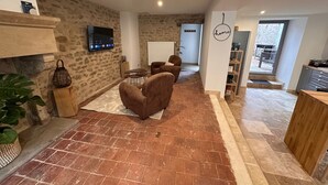 Un salon moderne avec un mur en pierre, un téléviseur à écran plat, des canapés en cuir marron, une table basse en bois et une grande plante en pot.