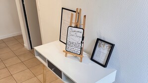 A white desk with a small easel holding a framed welcome sign and a framed picture. - Cosy house, parking, wifi near Luxembourg/metz/Amneville (Hayange)