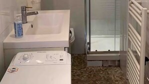 A bathroom with a white sink, a mirror, a glass shower enclosure, and a white toilet.