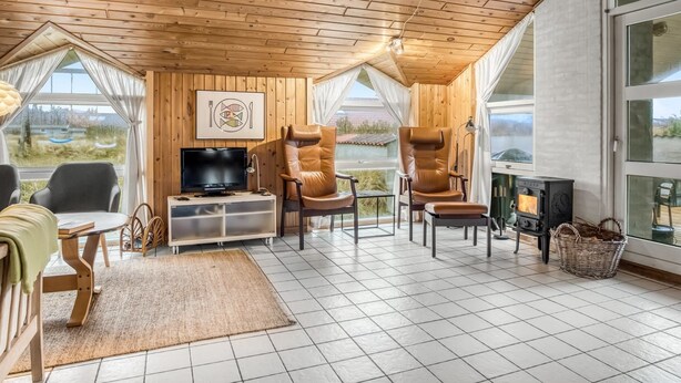 Un intérieur chaleureux en bois, avec un téléviseur, des fauteuils en cuir et une cheminée.