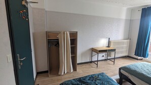 Ett sovrum med en säng, ett skrivbord, en garderob och ett element.