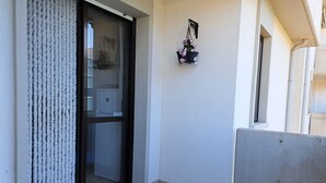 Un balcon avec une porte-fenêtre coulissante, une plante en pot et un revêtement de sol carrelé.