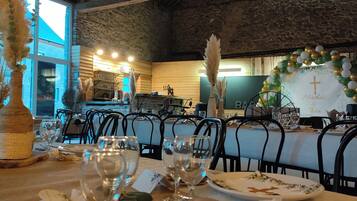 Een restaurant met rustieke houten balken en bakstenen muren, met een gedekte tafel voor een maaltijd, inclusief wijnglazen en borden.