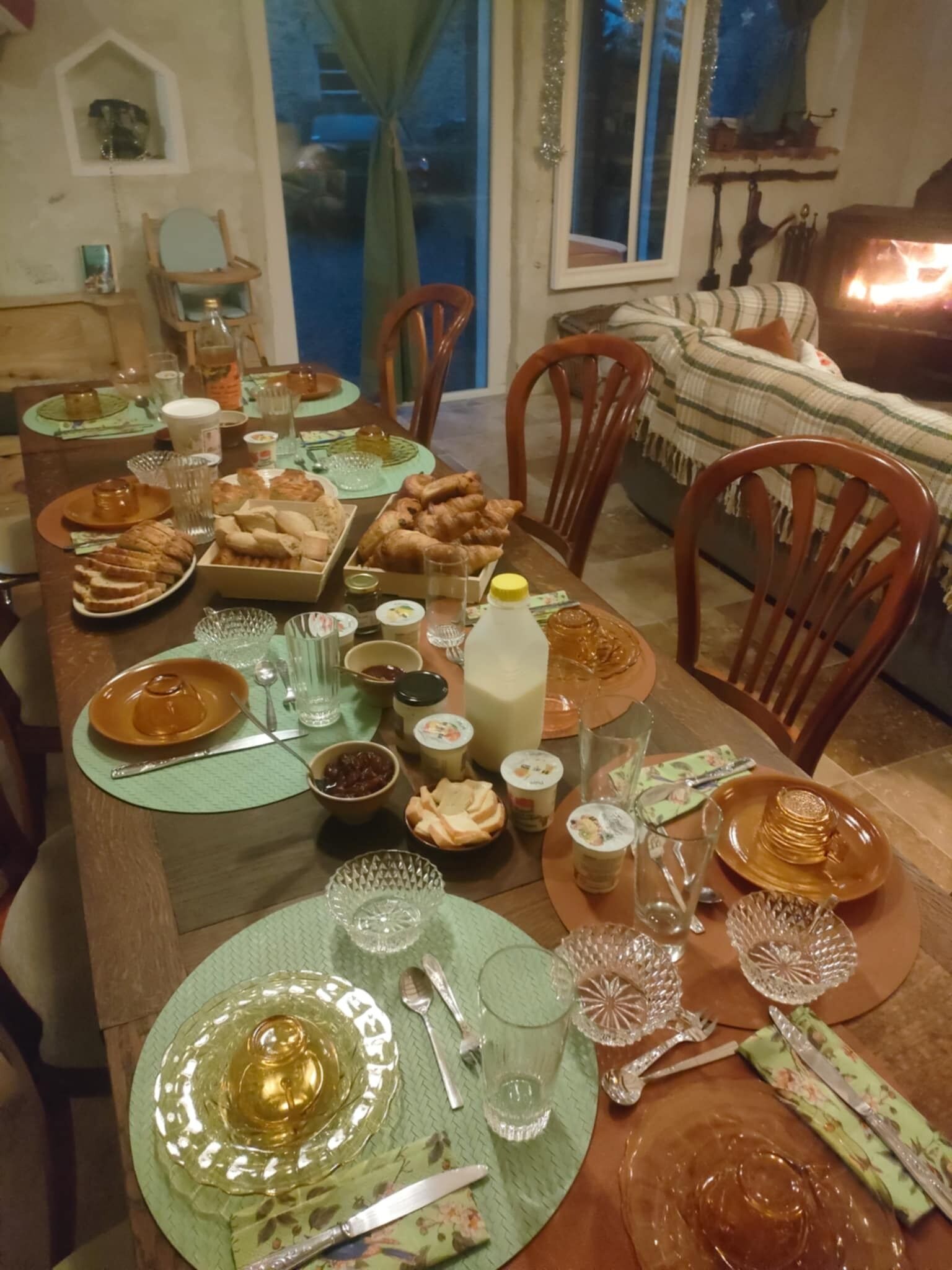 Ett matbord dukat med olika rätter, glas och bestick, omgivet av stolar och en soffa i ett mysigt rum.