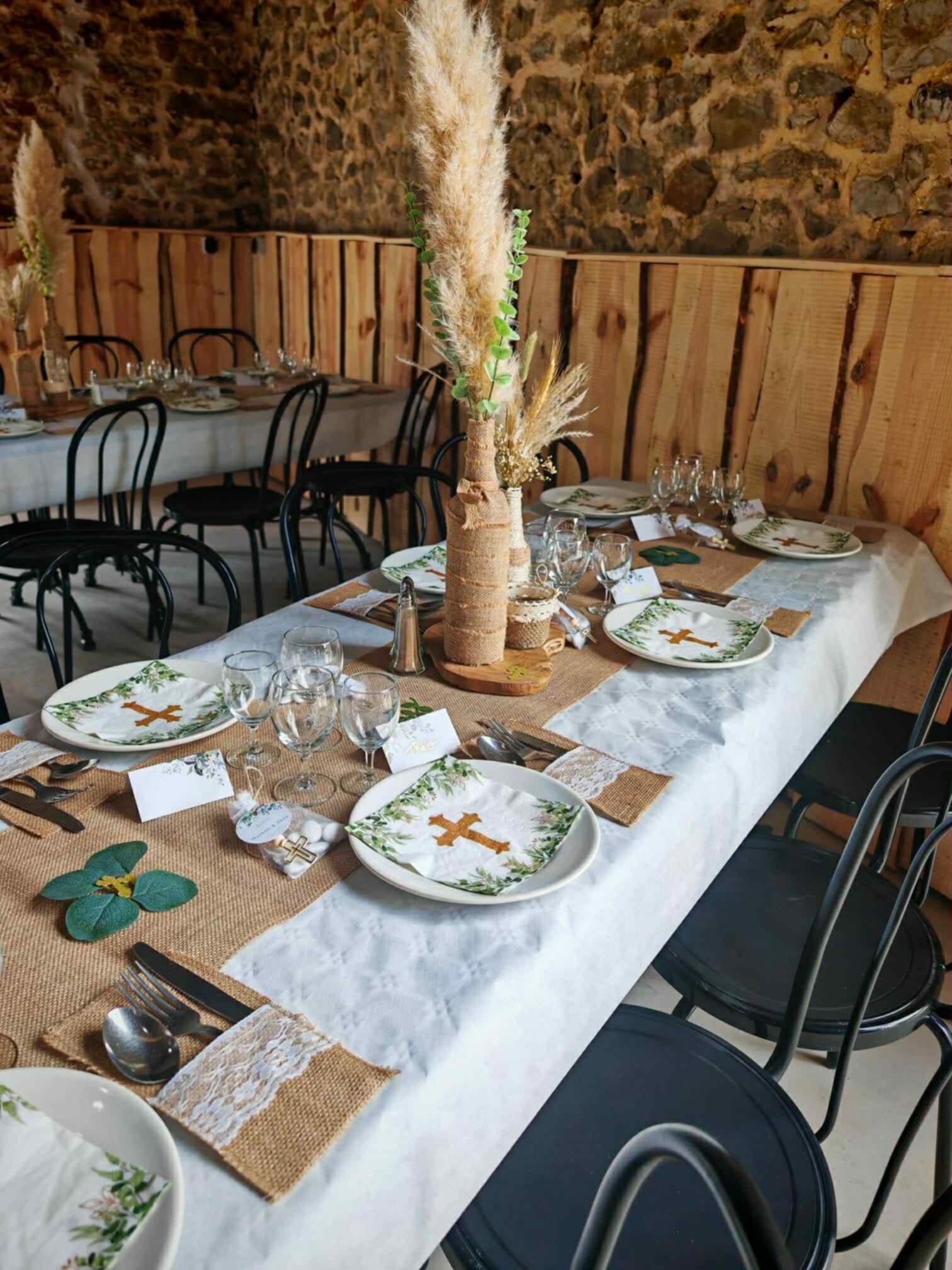 A long dining table set with plates, glasses, and cutlery, surrounded by chairs.