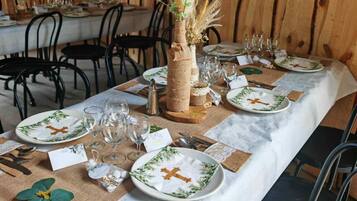 A long dining table set with plates, glasses, and cutlery, surrounded by chairs.