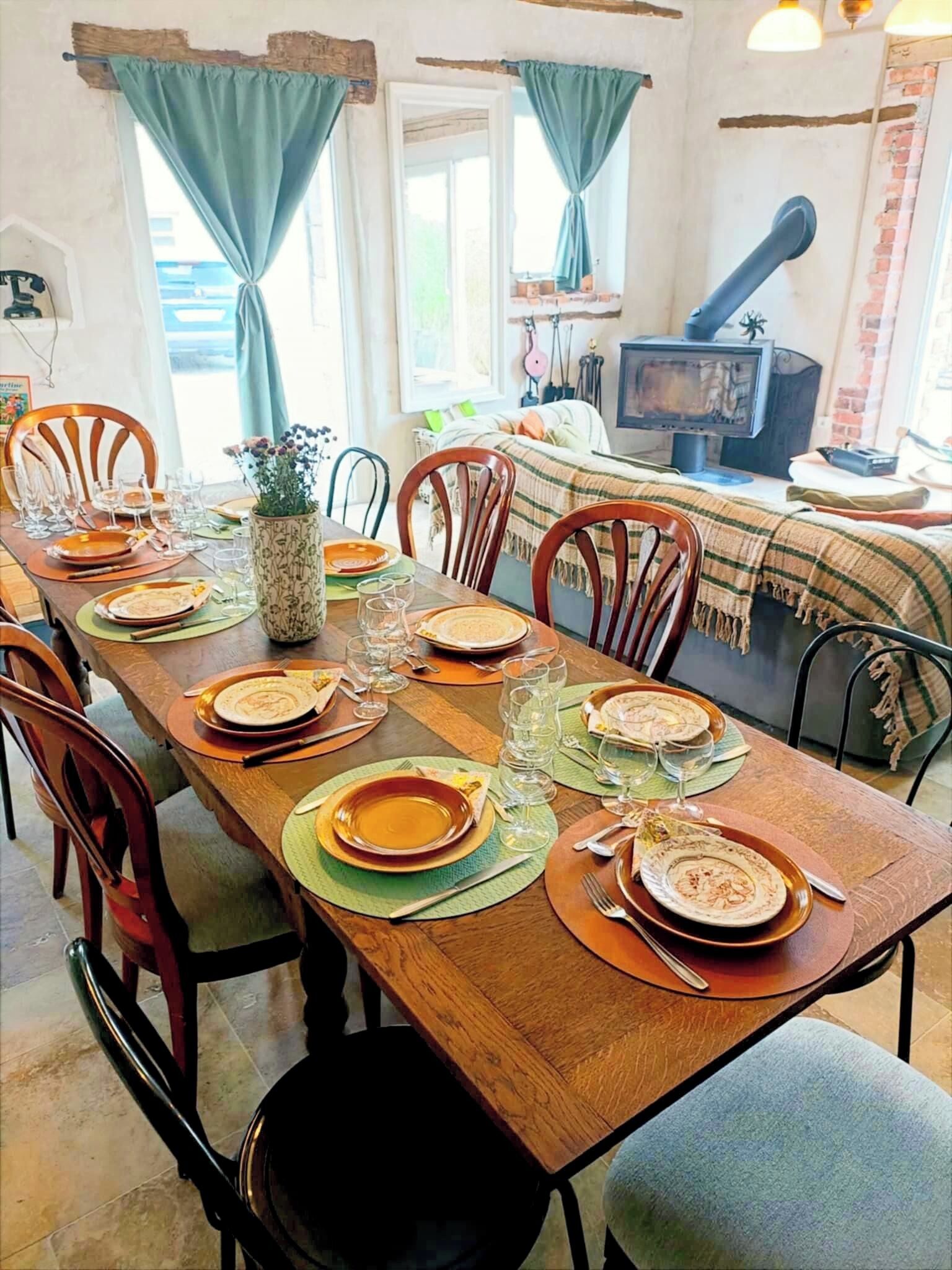 A dining area with a long wooden table set for a meal, surrounded by chairs.