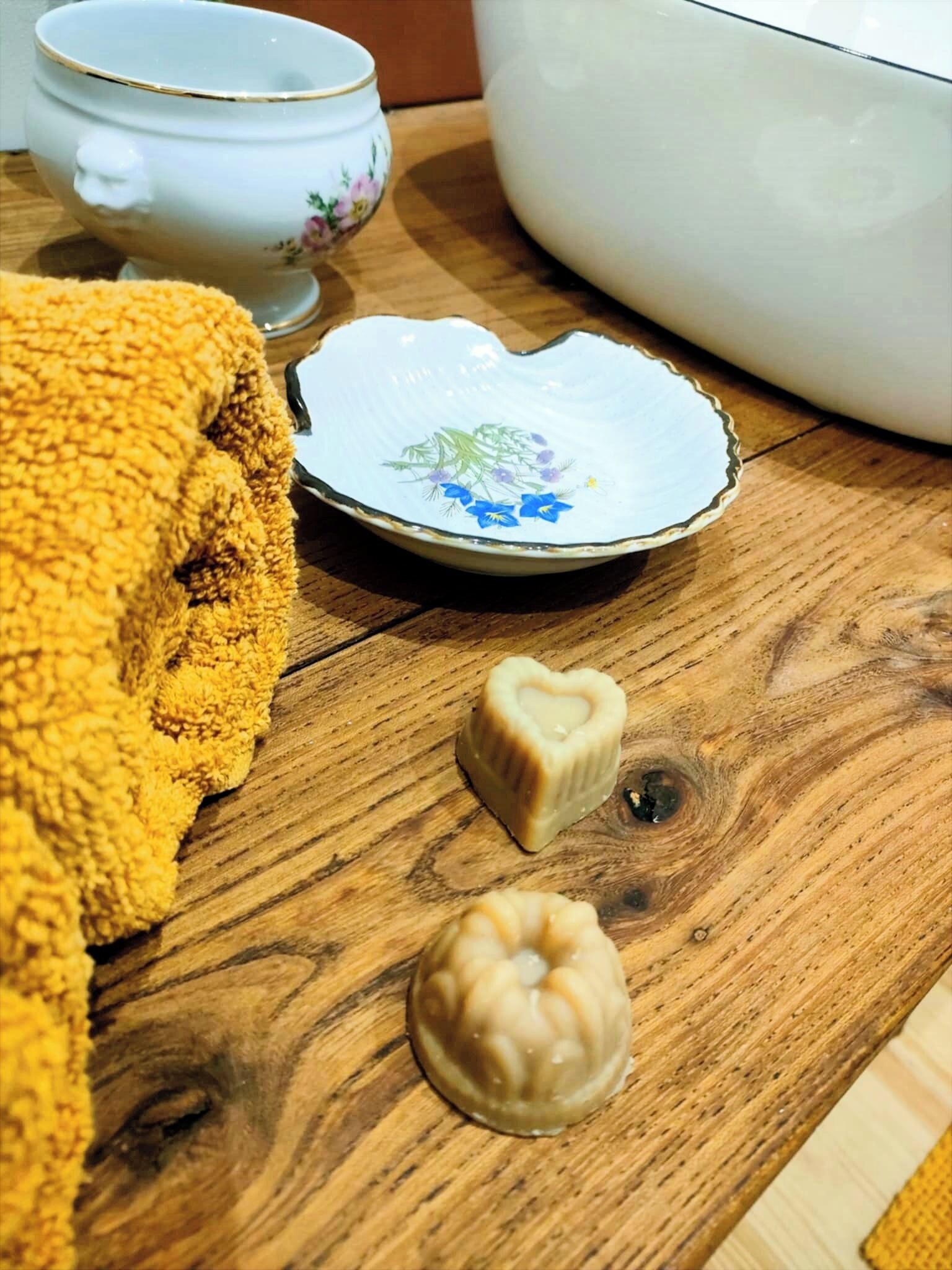 A wooden table with a white ceramic bowl, a decorative plate, and a yellow towel.