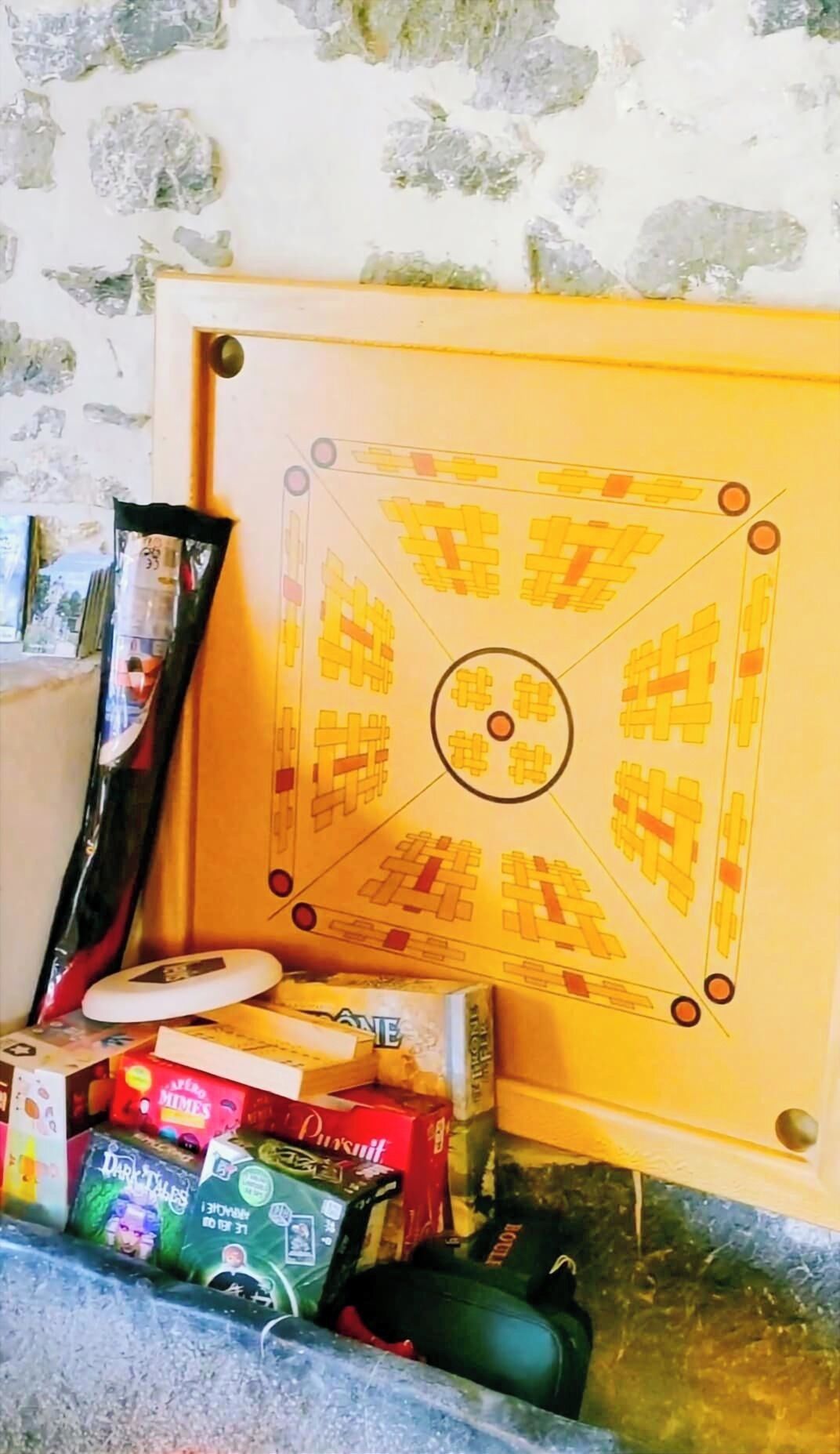 Ein gerahmtes Puzzle an der Wand, ein schwarzes Objekt lehnt dagegen, und darunter befinden sich verschiedene Snackboxen auf einem Regal.