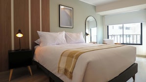 A bedroom with a bed, bedside lamps, a framed picture, a window with a view, and a mirror. - w *| Grand 1BR with Great Balcony in San Isidro (San Isidro)