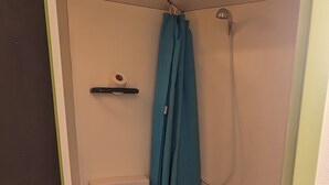 A small, enclosed bathroom with a toilet, a shower area, and a blue floor. - Le Balandri - Double hotel room (Lully)