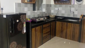 A modern kitchen with wooden cabinets, a black refrigerator, a gas stove, and a built-in oven. - Spacious 2BHK Mountain View | Near Palolem Beach (Canacona)