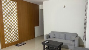 A living room with a grey sofa, a dark wooden coffee table, and a patterned partition. - Spacious 2BHK Mountain View | Near Palolem Beach (Canacona)