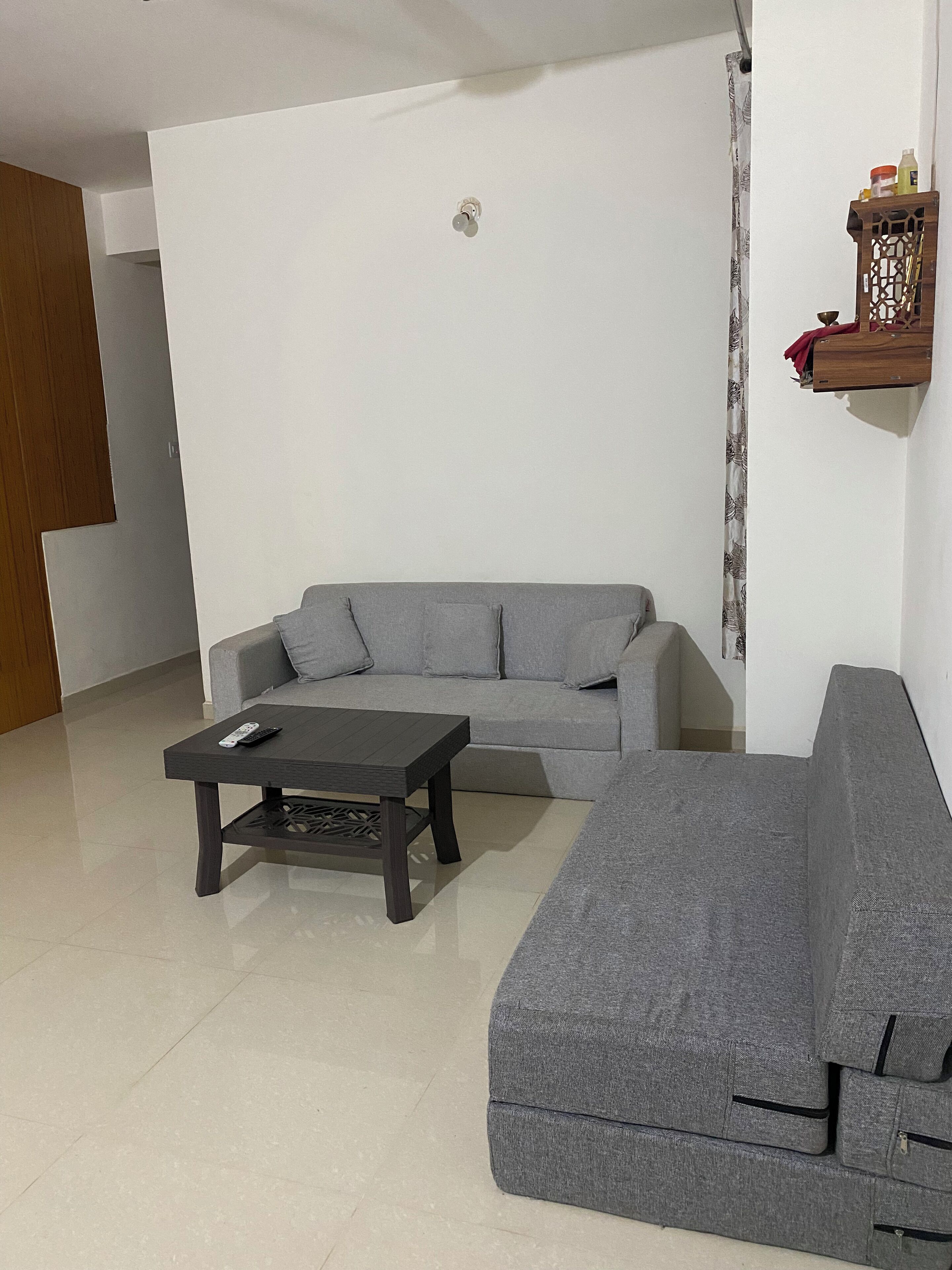 Una sala de estar con un sofá gris, un reposapiés a juego y una mesa de centro con mandos a distancia.
