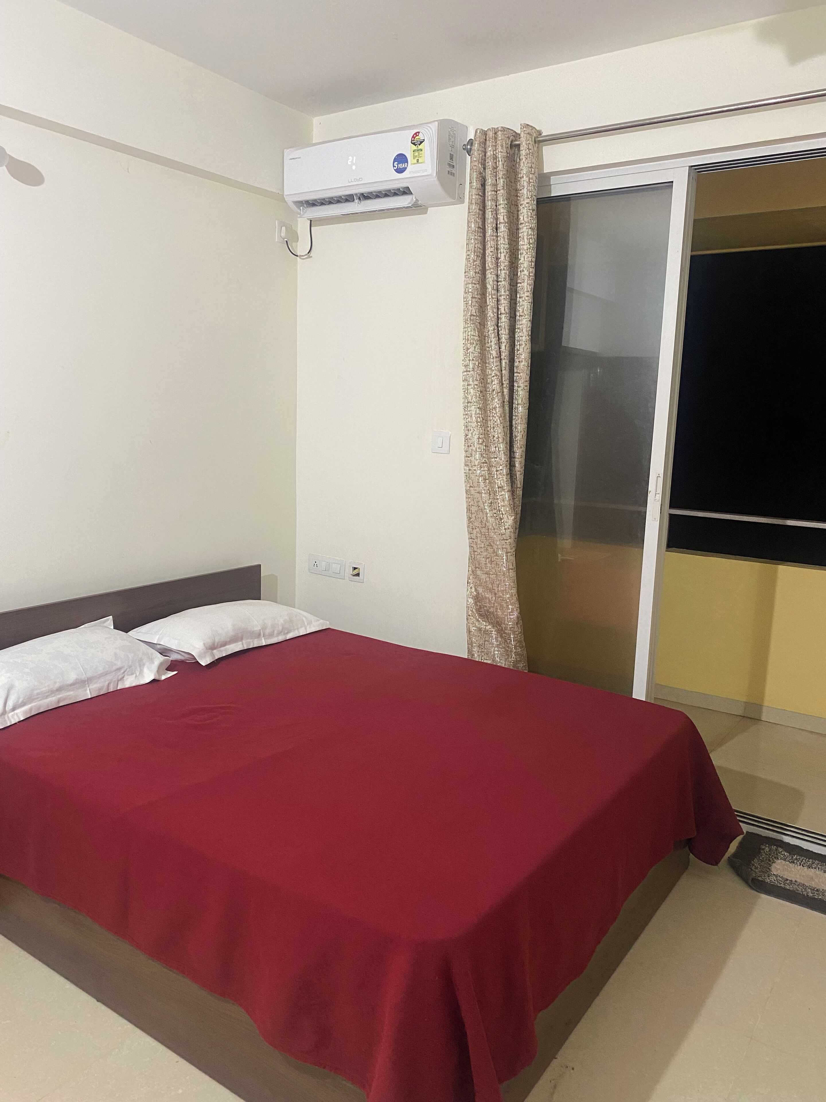 Camera d'albergo con un letto, condizionatore d'aria, una porta scorrevole in vetro e vista all'esterno.
