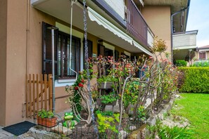 Um edifício residencial com varanda, plantas em vasos e um jardim.
