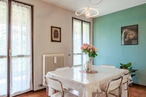 Un espace repas comprenant une table, des chaises, un vase de fleurs et un luminaire au plafond.