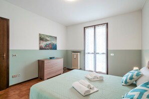 A bedroom with a bed, a dresser, a radiator, and a window with curtains.