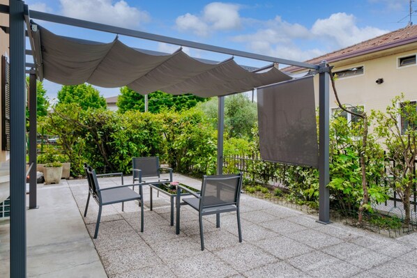 An outdoor patio with a table and chairs under a canopy.