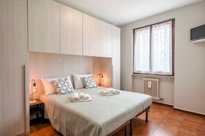 Une chambre à coucher avec un lit, des lampes de chevet, une fenêtre avec des rideaux et un radiateur.