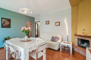Un área de comedor con una mesa y sillas, un sofá, una chimenea y una pared decorada con cuadros.