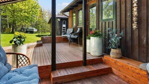 A wooden deck with a covered area, outdoor seating, and a view of a vehicle in the background. - Beautiful Holiday Home in Blokhus (Blokhus)