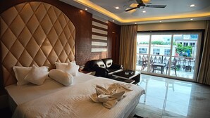 A modern hotel room with a large bed, a ceiling fan, and a view of the outside balcony. - Sagar Kuthi (Kanthi)