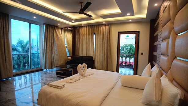 A modern bedroom with a large bed, a ceiling fan, and a view of the outdoors. - Sagar Kuthi (Kanthi)