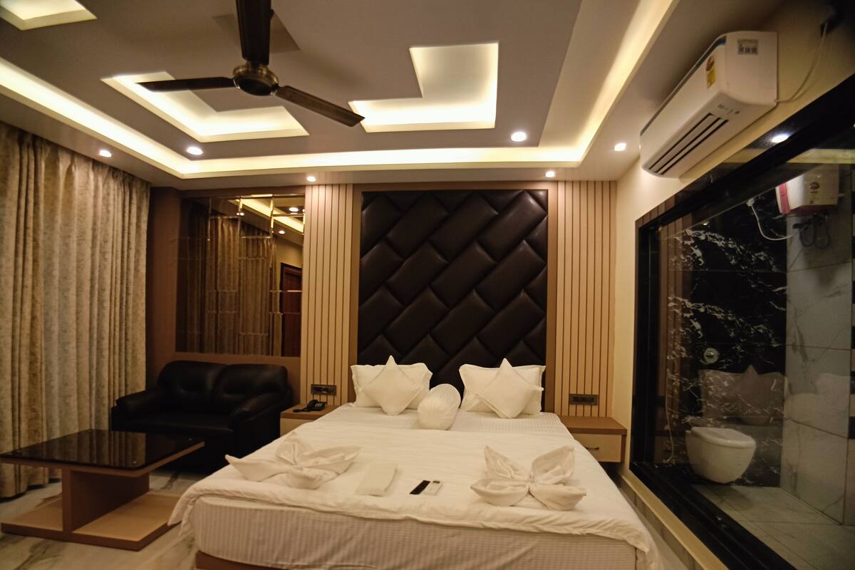 Ein modernes Hotelzimmer mit einem großen Bett, einem Deckenventilator, Einbautenbeleuchtung, einer Minibar und Blick auf die Stadt.