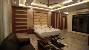 A modern bedroom with a large bed, a ceiling fan, recessed lighting, a TV, and a marble floor. - Sagar Kuthi (Kanthi)