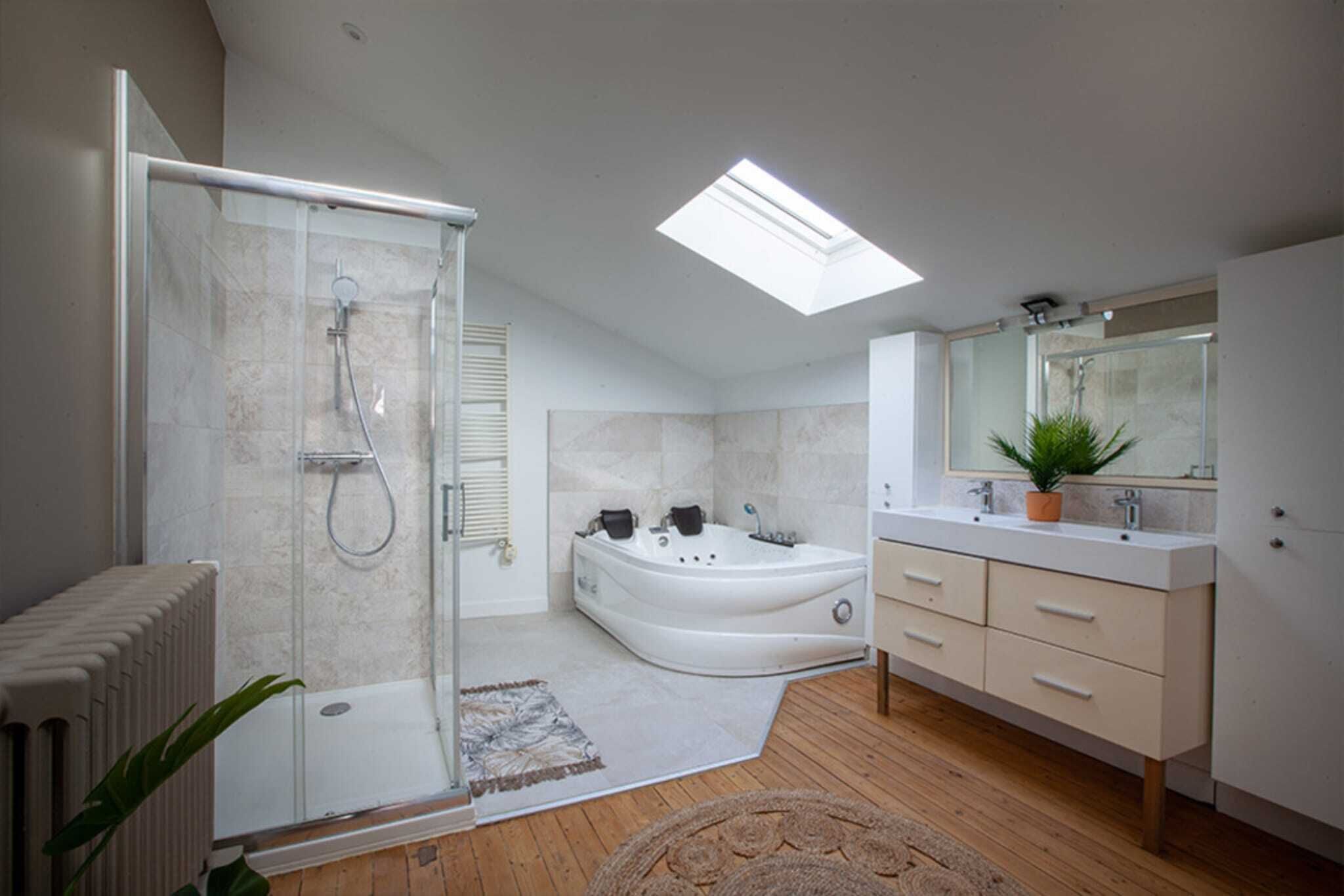 Une salle de bain moderne avec une douche à parois de verre, une baignoire sur pieds, un grand miroir et un plancher en bois.
