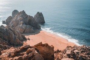 A coastal landscape with rocky formations and a sandy beach.
