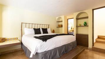 A neatly made bed with a headboard, a bedside table with a lamp, and a bench at the foot of the bed.