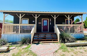 A wooden building with a porch, a red door, and a sign that reads "La Casa de la Llamada." - Cozy cabin in Garden City, TX with WiFi, AC/Heat, Full Kitchen and Laundry Cntr (Garden City)