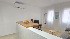 Un salon moderne avec un coin cuisine, comprenant un comptoir en bois, une table à manger et un canapé.
