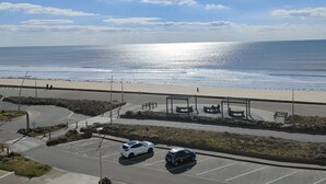 Un parking avec deux voitures, une plage et un ciel dégagé.