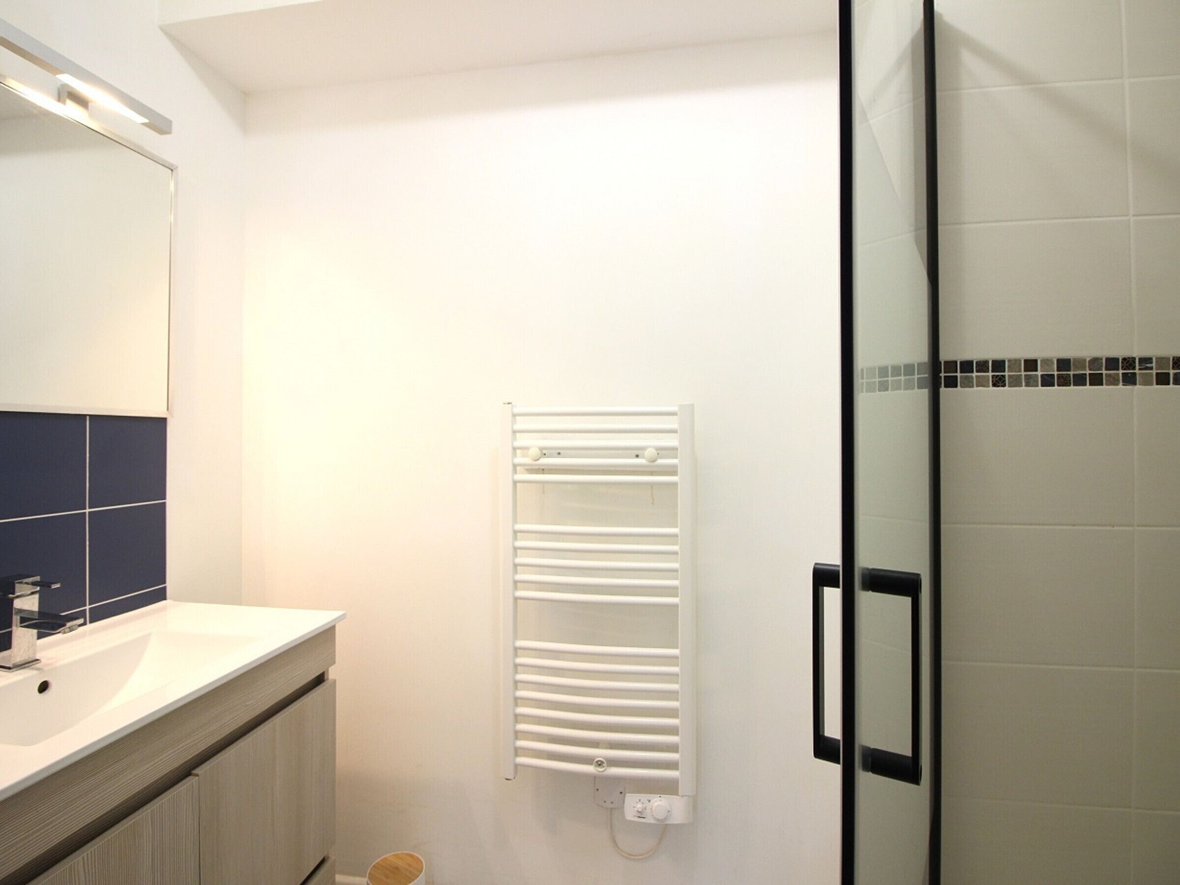 Une salle de bain moderne avec un lavabo blanc, un miroir et un porte-serviettes.