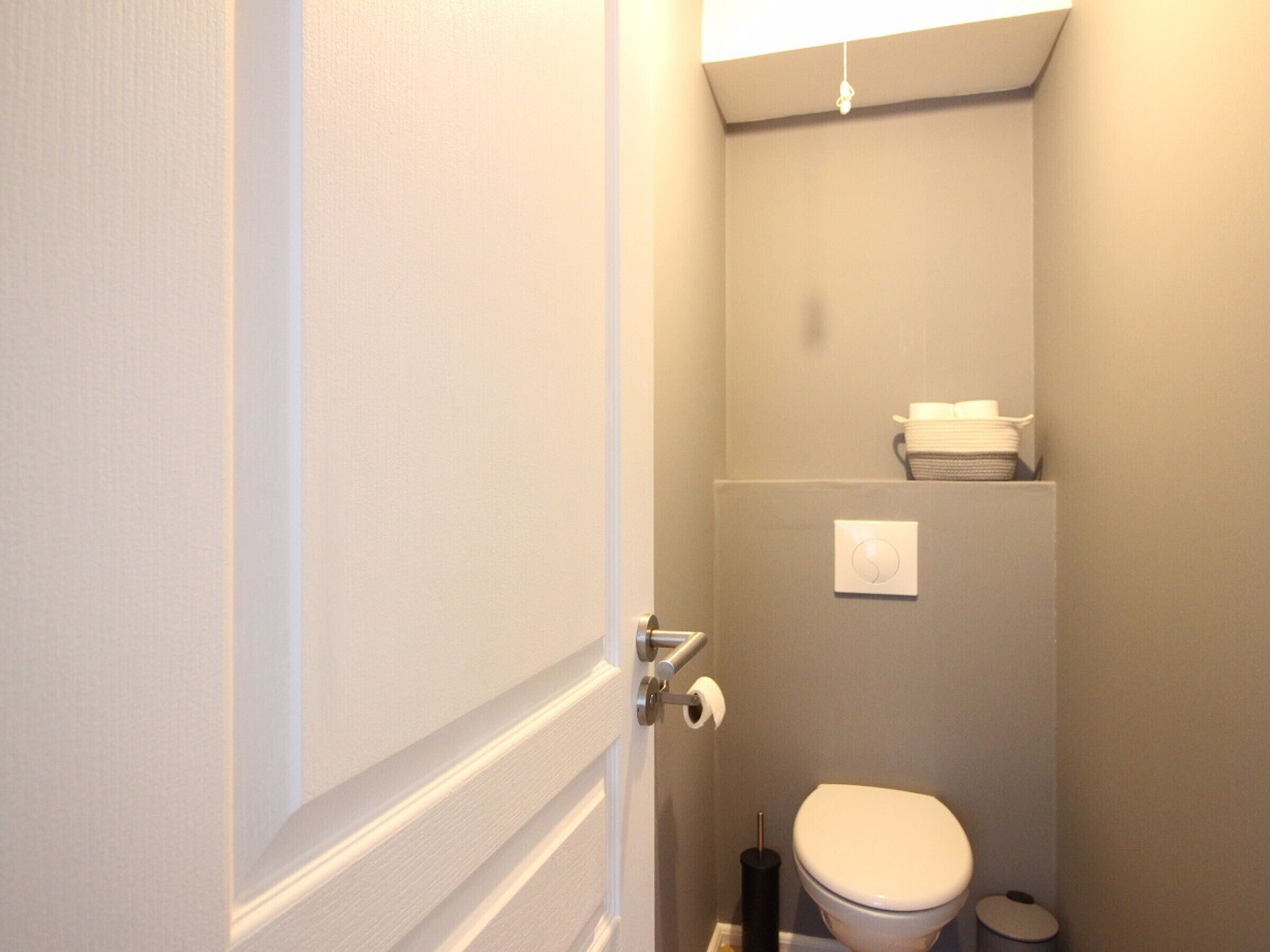 Un bagno piccolo e stretto, con il water, un porta asciugamani e un portasciugamani di carta.