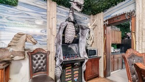 A room with a dinosaur statue, a fireplace, and a TV. - ★★ Gondor ★★. OSU Dragon Castle Barcade (Columbus)