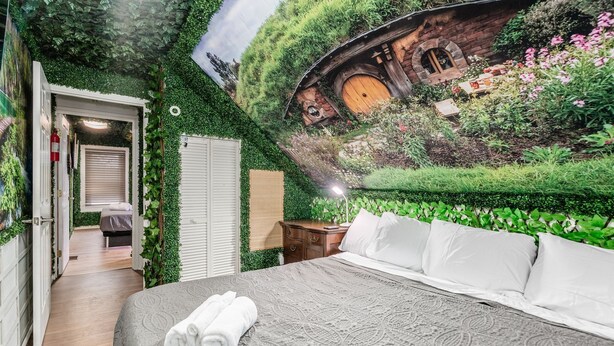 A bedroom with a bed, a nightstand, and a wall mural of a house. - ★★ Gondor ★★. OSU Dragon Castle Barcade (Columbus)