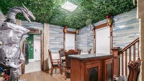 A room with a wooden desk, chairs, a green leafy ceiling, and a dragon sculpture. - ★★ Gondor ★★. OSU Dragon Castle Barcade (Columbus)
