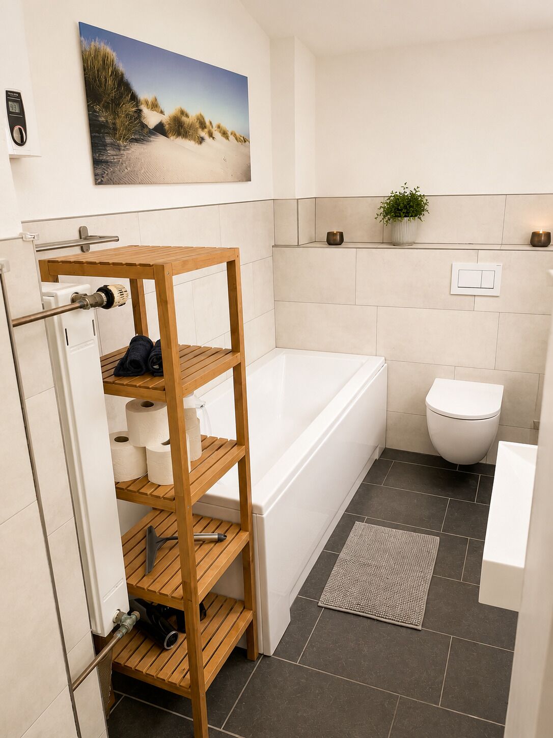 A modern bathroom with a wooden shelf unit, a bathtub, a toilet, and a wall-mounted plant.
